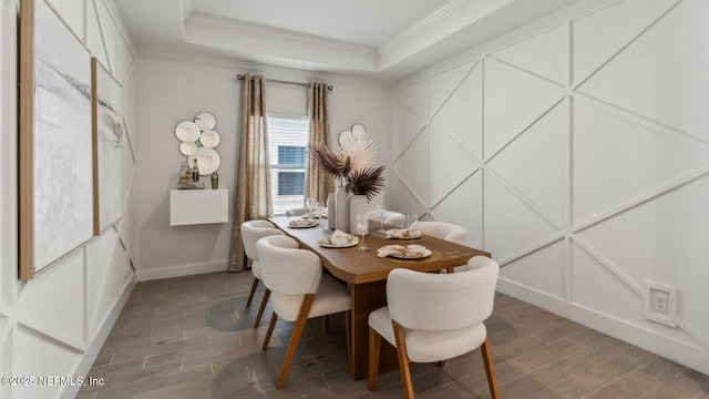 dining space with ornamental molding and a raised ceiling