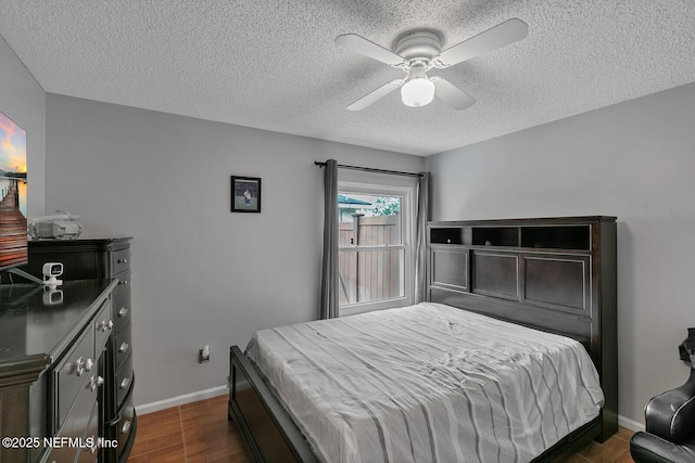 bedroom with a textured ceiling, ceiling fan, and dark wood-type flooring