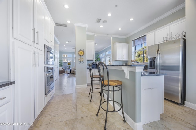 kitchen featuring light tile patterned floors, dark stone countertops, appliances with stainless steel finishes, white cabinets, and ornamental molding