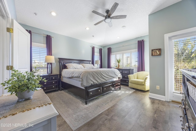 bedroom with ceiling fan, dark hardwood / wood-style flooring, a textured ceiling, and multiple windows