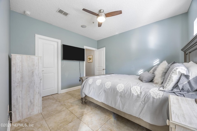 bedroom featuring ceiling fan, light tile patterned floors, and a textured ceiling