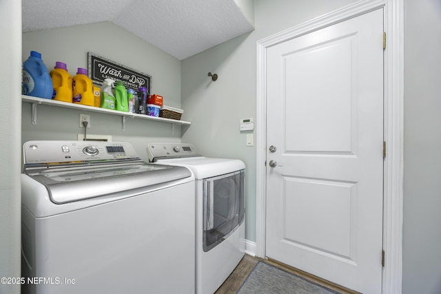 clothes washing area featuring a textured ceiling and washer and clothes dryer