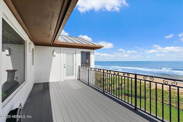 wooden terrace featuring a beach view and a water view