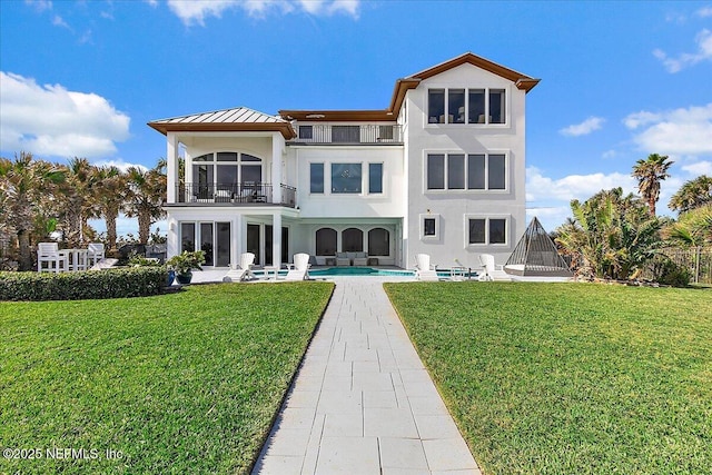 back of property featuring a yard, a balcony, and a patio area