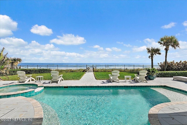 view of pool with an in ground hot tub, a water view, a patio area, and a lawn