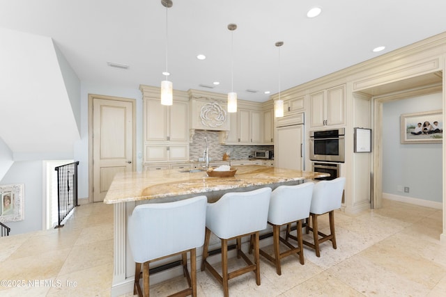 kitchen featuring light stone counters, stainless steel double oven, paneled built in refrigerator, cream cabinets, and hanging light fixtures