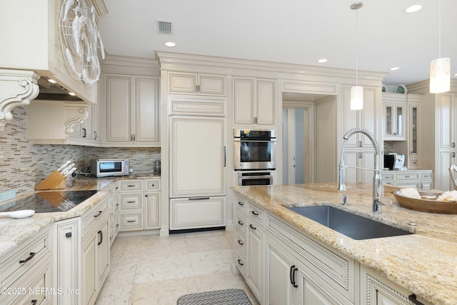 kitchen featuring pendant lighting, sink, black electric cooktop, tasteful backsplash, and light stone counters