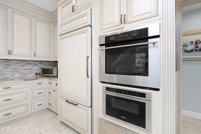 kitchen featuring light stone countertops, stainless steel double oven, tasteful backsplash, and paneled built in fridge