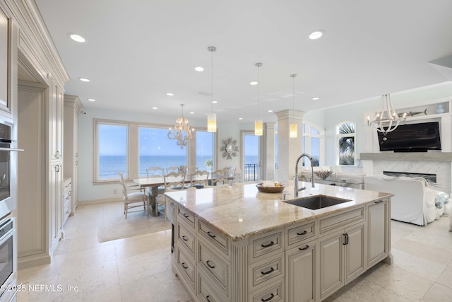 kitchen with a center island with sink, decorative light fixtures, a healthy amount of sunlight, and sink