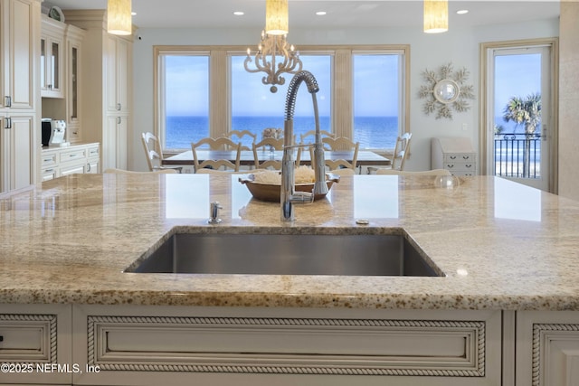 kitchen with sink, a water view, and hanging light fixtures