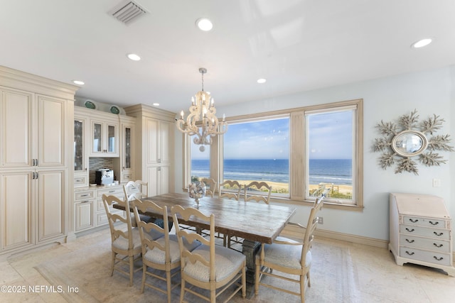 dining space featuring a chandelier, a water view, and a beach view