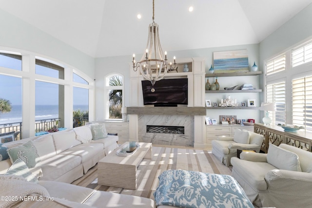 living room with a notable chandelier, lofted ceiling, and a premium fireplace