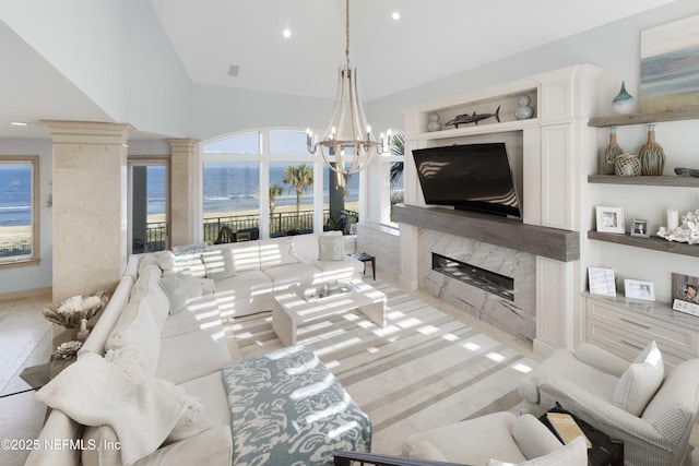 living room featuring built in shelves, a high end fireplace, decorative columns, a chandelier, and lofted ceiling