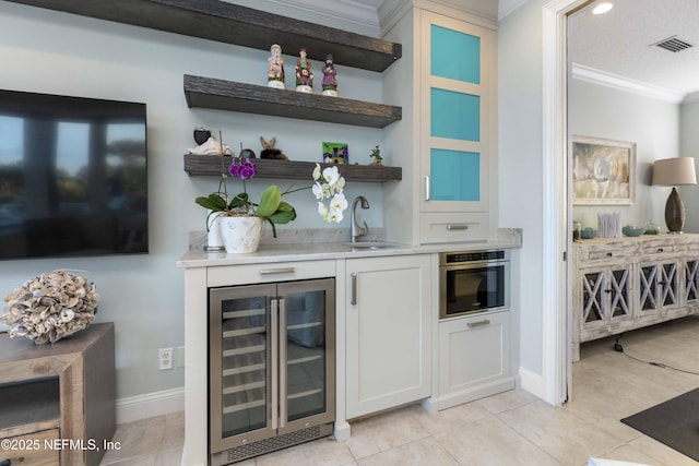 bar featuring wine cooler, ornamental molding, stainless steel oven, sink, and white cabinetry