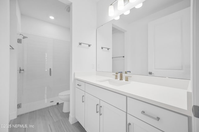 bathroom featuring vanity, toilet, and a shower with door