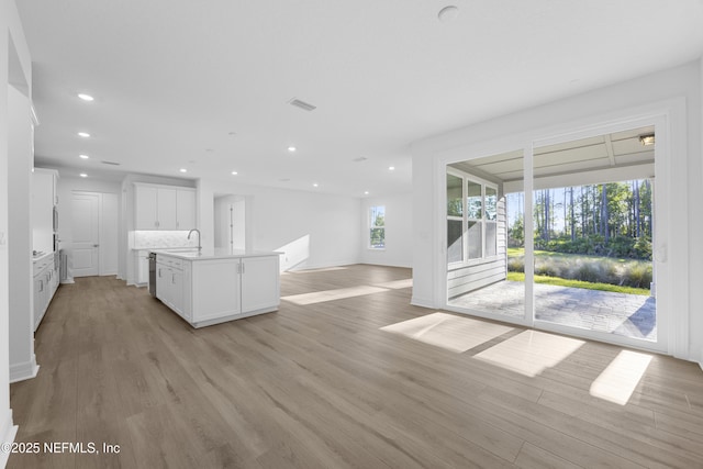 kitchen featuring a center island with sink, white cabinets, light hardwood / wood-style floors, and sink