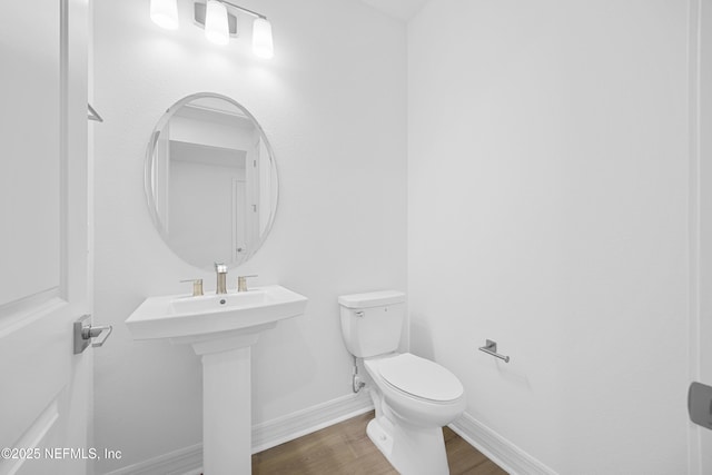 bathroom featuring wood-type flooring, toilet, and sink