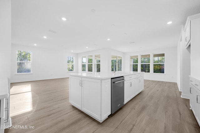 kitchen with light hardwood / wood-style floors, sink, white cabinetry, and a kitchen island with sink