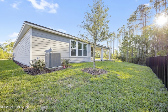 back of house with central AC and a lawn