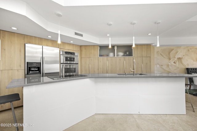 kitchen featuring stainless steel appliances, a kitchen bar, sink, and hanging light fixtures