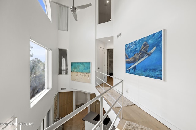 stairway featuring ceiling fan, a towering ceiling, and wood-type flooring