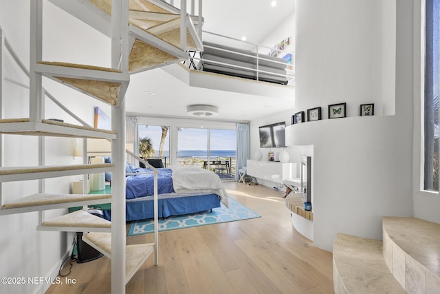 bedroom featuring a high ceiling and light hardwood / wood-style floors