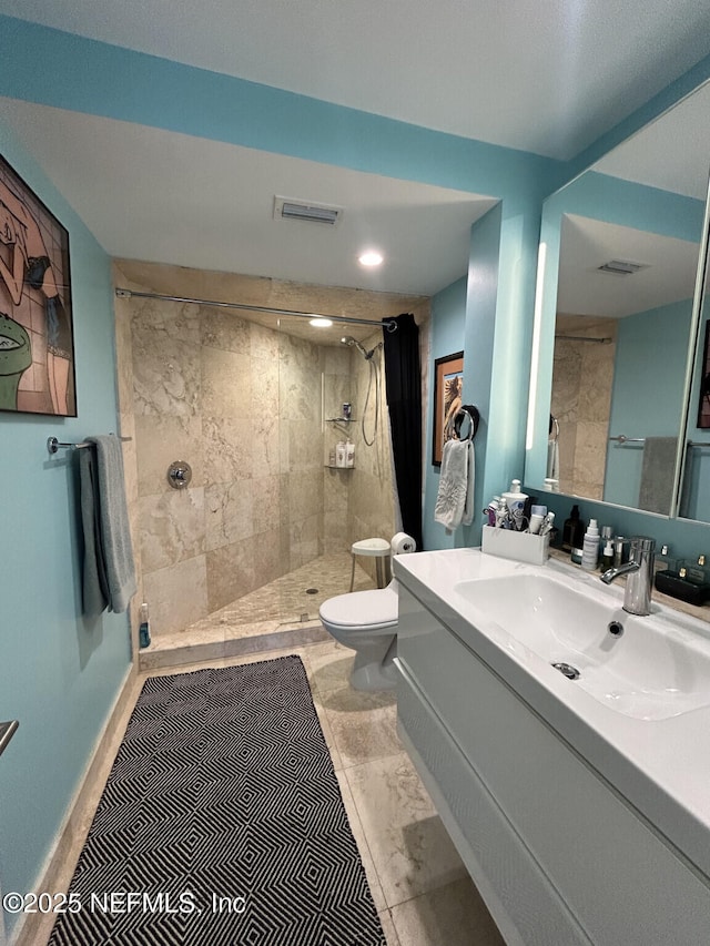 bathroom featuring vanity, tiled shower, tile patterned floors, and toilet