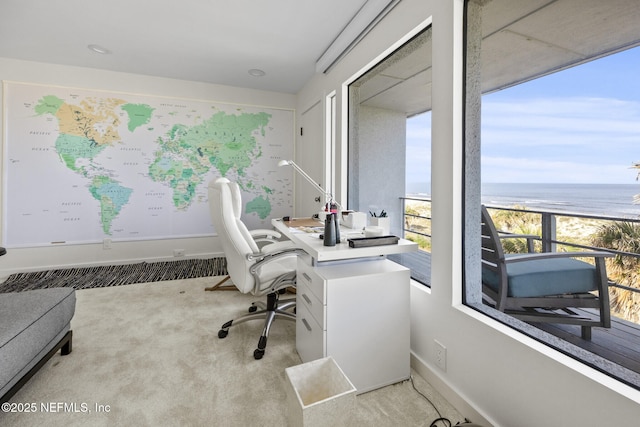 office featuring a water view, light colored carpet, and a beach view