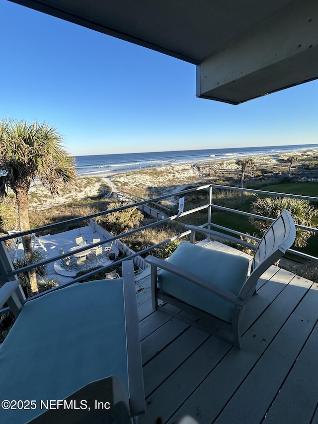 wooden deck featuring a water view and a beach view