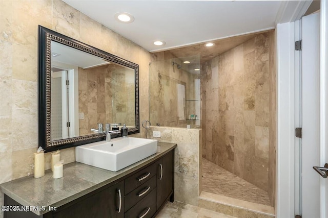 bathroom featuring vanity, tiled shower, and tile walls