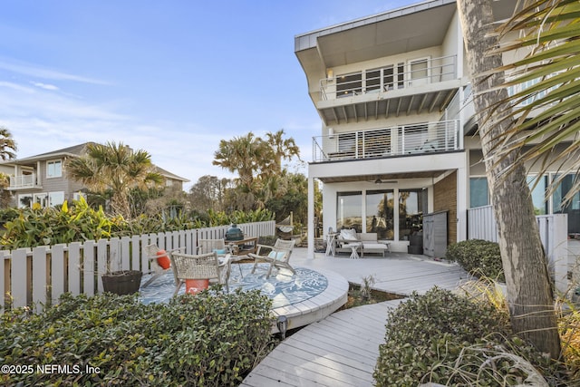 back of house featuring a balcony, outdoor lounge area, and a deck