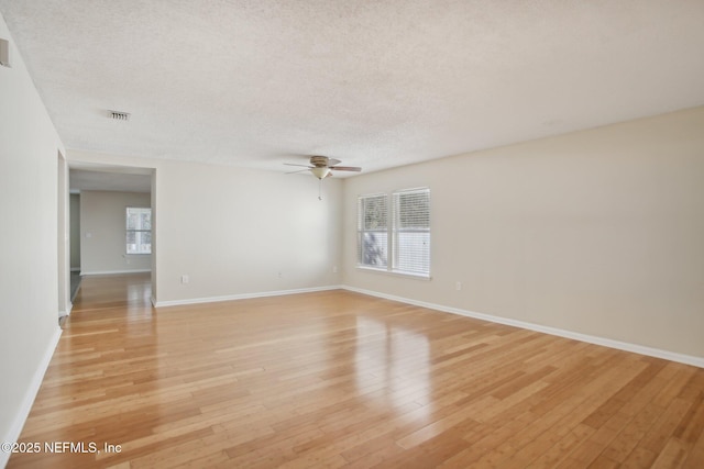 spare room featuring ceiling fan, light wood-type flooring, and a textured ceiling