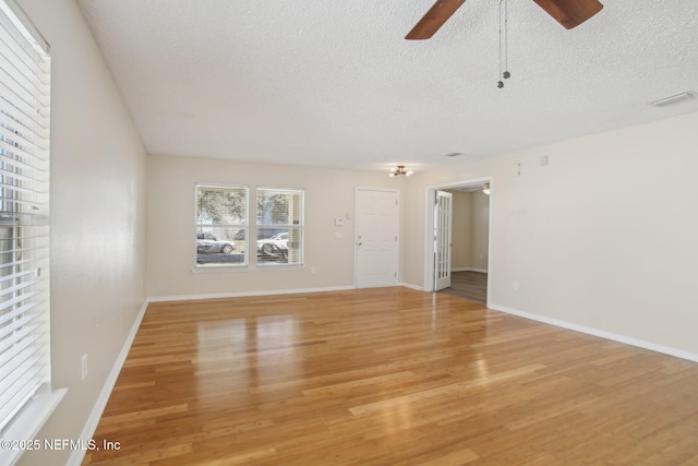 empty room with a textured ceiling, light hardwood / wood-style floors, and ceiling fan