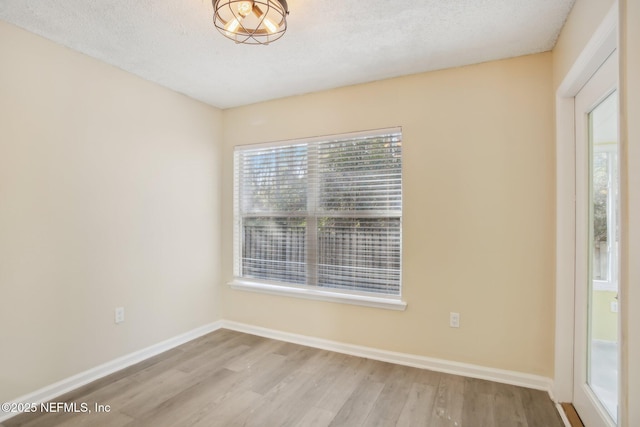 empty room with light hardwood / wood-style flooring and a textured ceiling