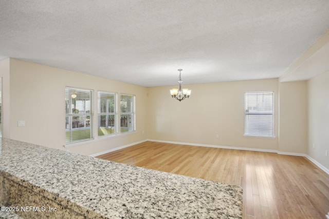 interior space featuring a chandelier, a textured ceiling, and light wood-type flooring