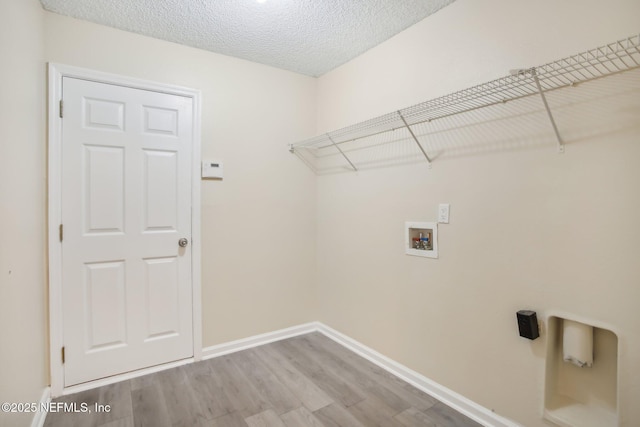 clothes washing area with washer hookup, a textured ceiling, and hardwood / wood-style flooring