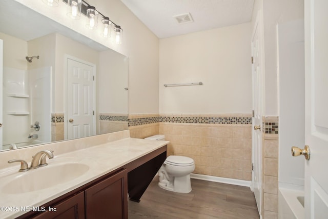 full bathroom with shower / bath combination, vanity, hardwood / wood-style flooring, tile walls, and toilet