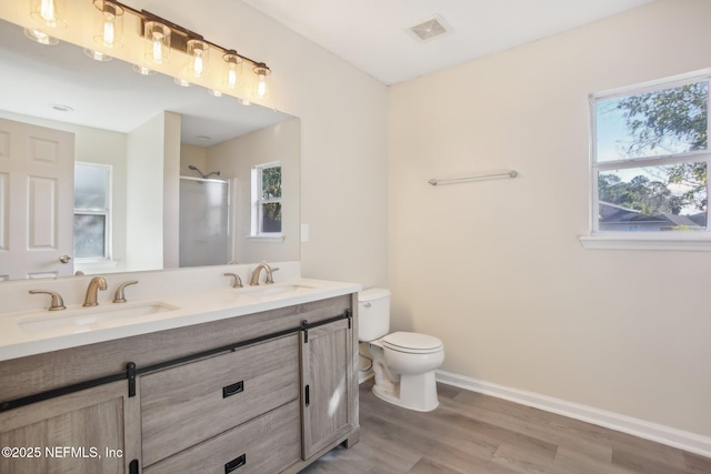 bathroom with vanity, hardwood / wood-style flooring, toilet, a healthy amount of sunlight, and a shower with shower door