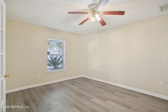 empty room featuring ceiling fan, light hardwood / wood-style flooring, and a textured ceiling