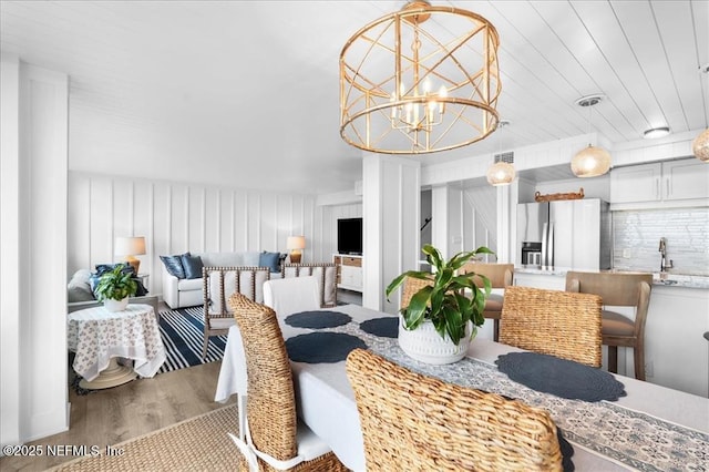 dining area with wooden ceiling, a notable chandelier, sink, and light hardwood / wood-style floors