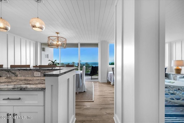 kitchen featuring pendant lighting, white cabinets, dark stone countertops, light wood-type flooring, and floor to ceiling windows