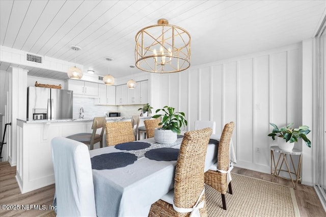 dining space with a chandelier, wood ceiling, light hardwood / wood-style floors, and sink