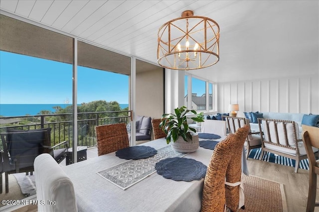 sunroom / solarium featuring an inviting chandelier and a water view