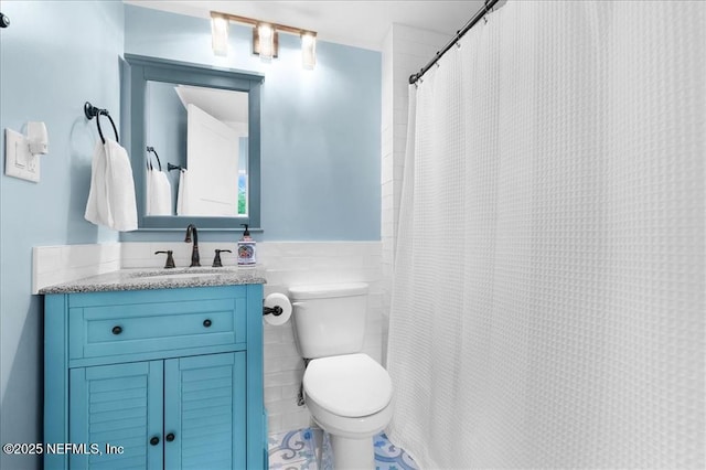 bathroom featuring toilet, tile walls, vanity, and curtained shower