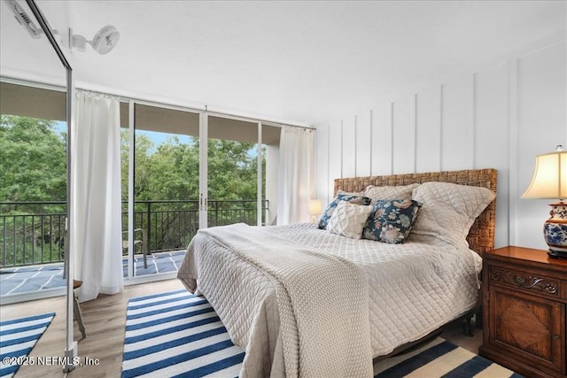 bedroom featuring light wood-type flooring, access to exterior, and multiple windows