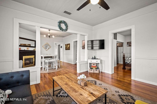 living room featuring a fireplace, ceiling fan with notable chandelier, and hardwood / wood-style flooring