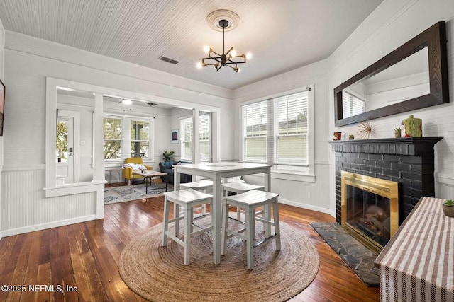 dining area featuring a fireplace, dark wood-type flooring, and an inviting chandelier