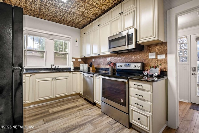 kitchen with cream cabinets, sink, light hardwood / wood-style flooring, and appliances with stainless steel finishes