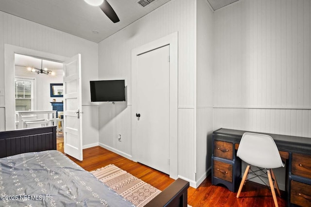 bedroom with ceiling fan with notable chandelier and dark hardwood / wood-style floors