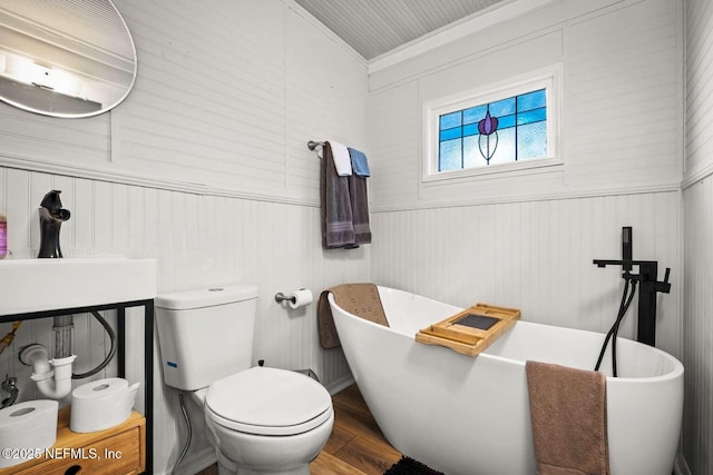 bathroom with a bathtub, toilet, wood-type flooring, and ornamental molding